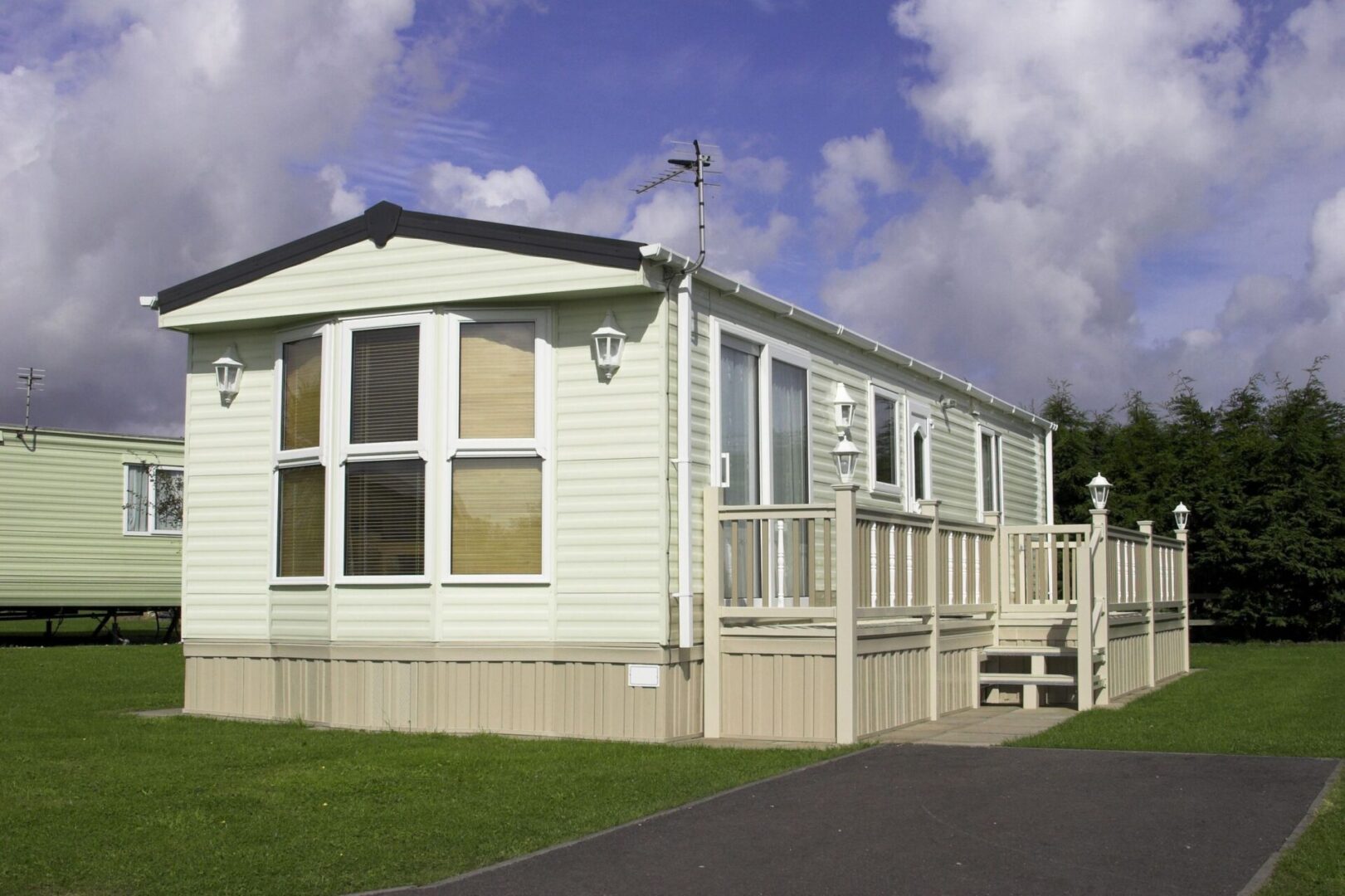 A white mobile home with a porch and a blue sky