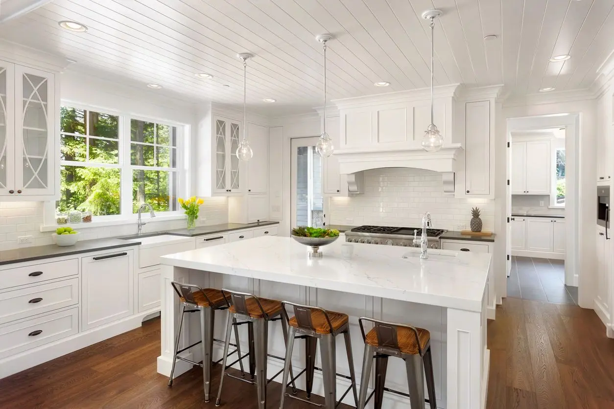 A kitchen with white cabinets and wooden floors.